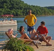 A group of guests relaxing on the sun deck as their extended family passes in a resort rental boat behind.