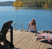 A women sits on the edge of our dock and dangles her feet in the cool clear water of Beaver Lake.