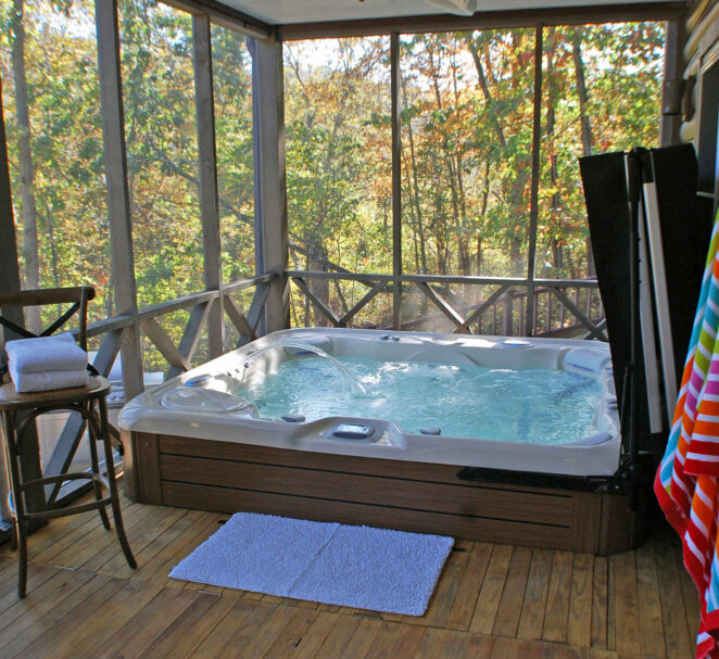 Sunbeams through the trees light up the crystal clear 10 person hot tub as it bubbles and jets. Colorful beach towels hang on the wall of the screened in porch that overlooks the lake.