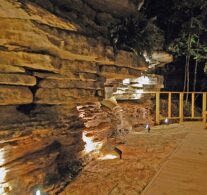 Mood lighting brings out features and shadows in the 14' tall natural bluff that forms one side of the private patio behind the Bluff Cabin.