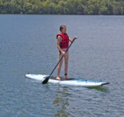 A women on a warm summer day enjoying one of our complimentary paddle boards on a calm day on Beaver Lake.