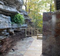 Sunlight reflects off the stream of water from the raindrop shower head on the Bluff Cabin's outdoor shower surrounded by natural limestone bluffs.